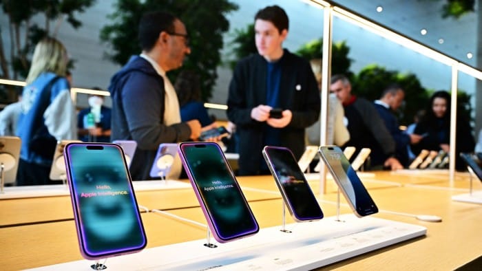 People stand behind a display of iPhones  at an Apple Store