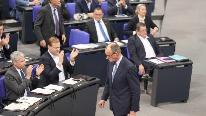 Christian Democrat leader Fredrich Merz walks past Alternative for Germany politicians in parliament as they cheer and clap after the vote in favour of a tighter migration policy