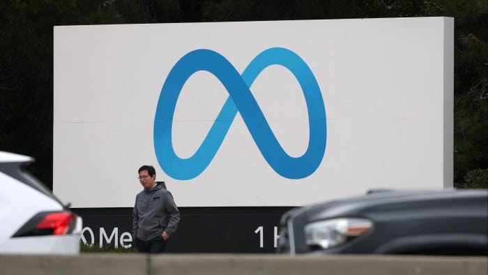 A visitor stands by a sign posted in front of Meta headquarters in Menlo Park, California