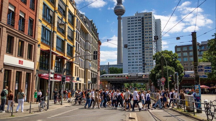 People cross a busy junction in Berlin, Germany