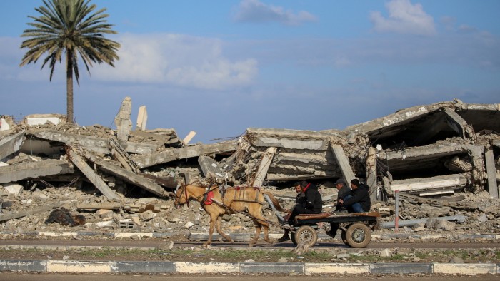 Civilians on a cart pass the rubble of a destroyed building in Gaza