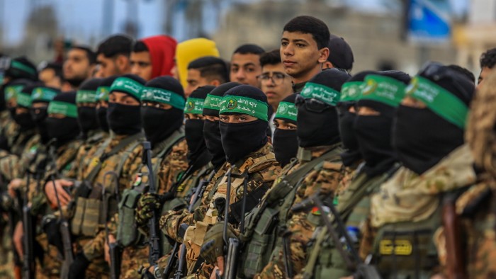 Qassam brigades, the military wing of Hamas, form a corridor as Israeli hostages are delivered to representatives of the International Committee of the Red Cross on February 8 2025 in Gaza