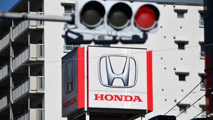 The Honda logo prominently displayed on the roof of a building with a red traffic light visible in the foreground and an apartment building in the background