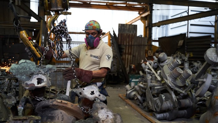 An employee moves a cast steel part from a pulley at a manufacturing facility in San Luis Potosi, Mexico,