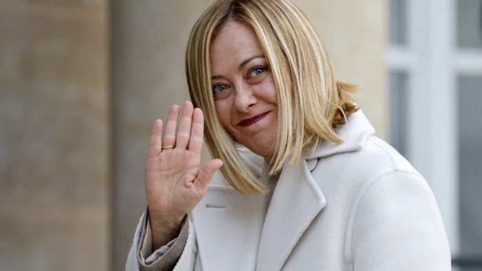 Giorgia Meloni smiles and waves as she arrives at the Élysée Palace in Paris