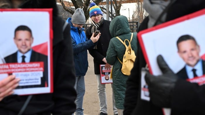 Supporters of Rafał Trzaskowski hold up banners with his picture