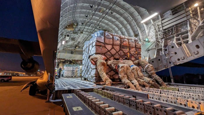 Personnel are seen loading equipment and supplies on to a transport plane