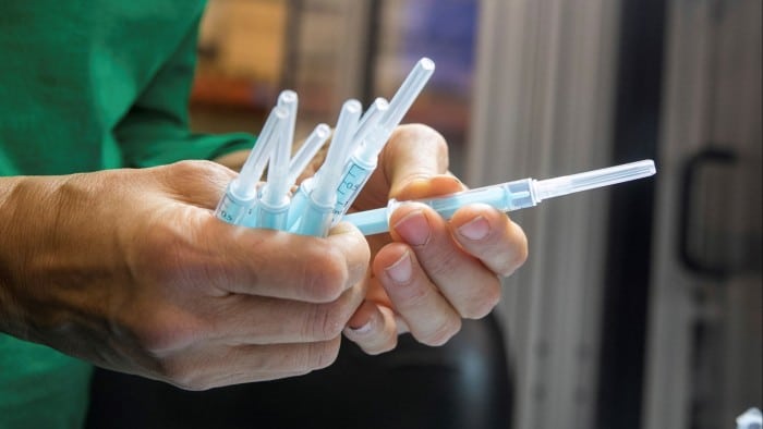 An operator at the Becton Dickinson plant in Fraga, Huesca, Spain, holds several vaccine injection devices