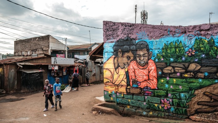 Children stand near a grafitti mural in Kibera