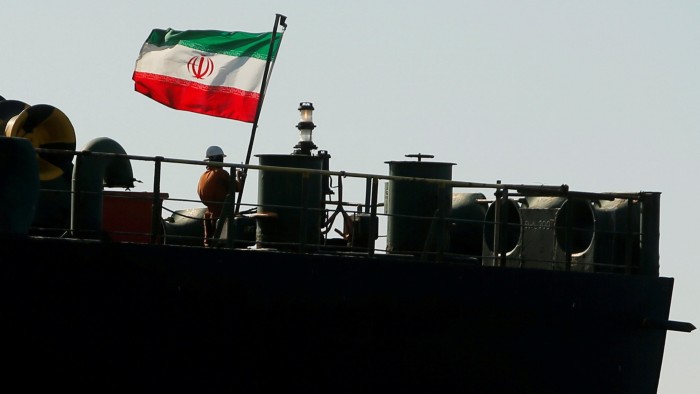 A crew member raises the Iranian flag on an Iranian tanker