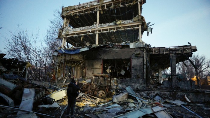 A person stands amid debris, examining the wreckage of a heavily damaged building in Kyiv following a Russian missile strike.