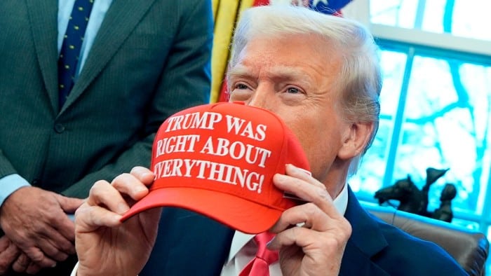 US President Donald Trump holds a hat reading ‘Trump was right about everything’ after signing Executive Orders in the Oval Officea