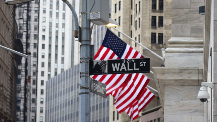 Wall Street sign with American flags near the New York Stock Exchange