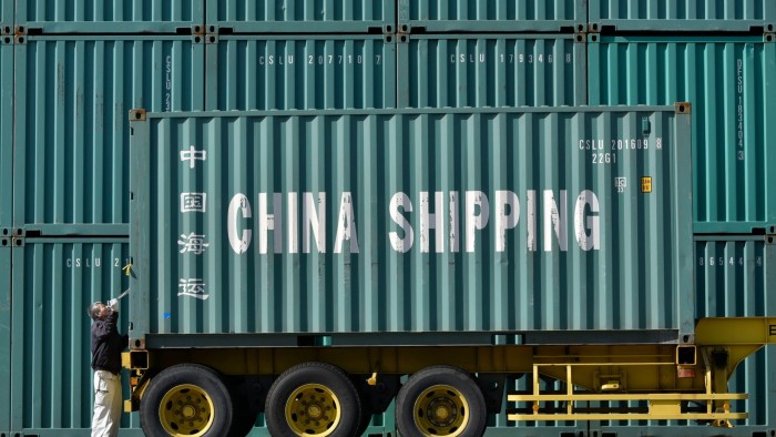 A worker inspects a shipping container marked ‘China shipping’