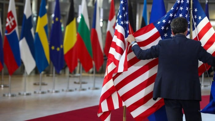 Flags of European nations and the US are displayed in Brussels