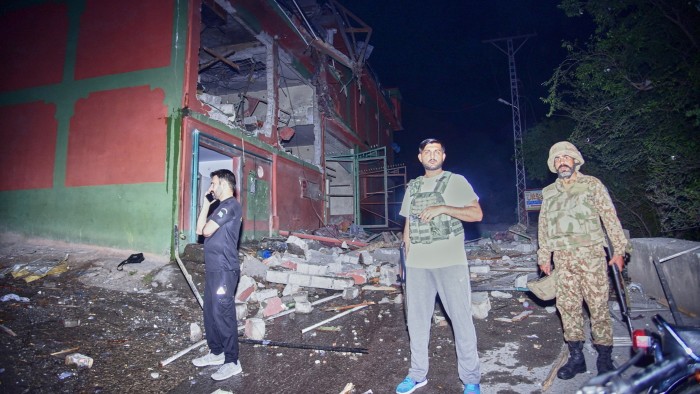 Security force officials stand outside a damaged building