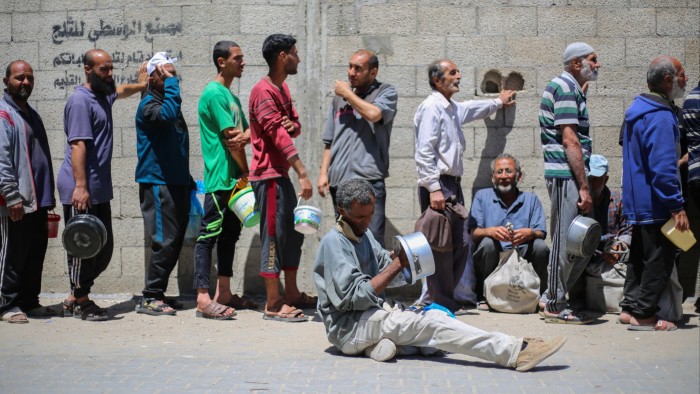Palestinians queue for a hot meal at a charity kitchen run by the UN’s World Food Programme at a refugee camp in the Gaza Strip