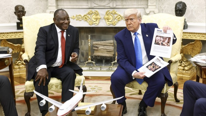 US President Donald Trump (R) holds up news articles related to violence in South Africa during a meeting with South Africa’s President Cyril Ramaphosa