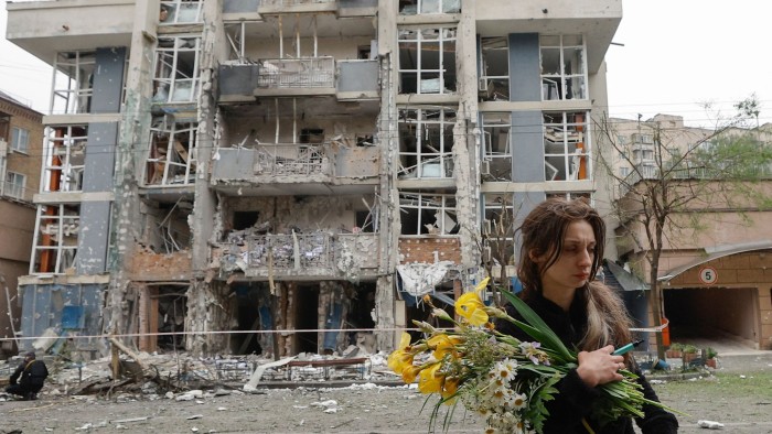 A woman walks past a building that has been struck by a drone
