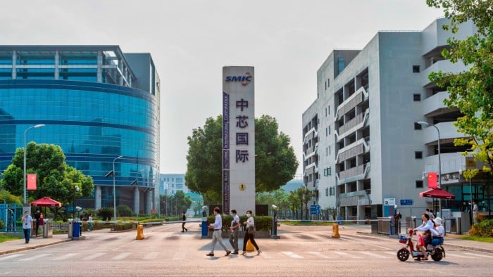 People walk in front of the gate of the SMIC factory in Shanghai, China