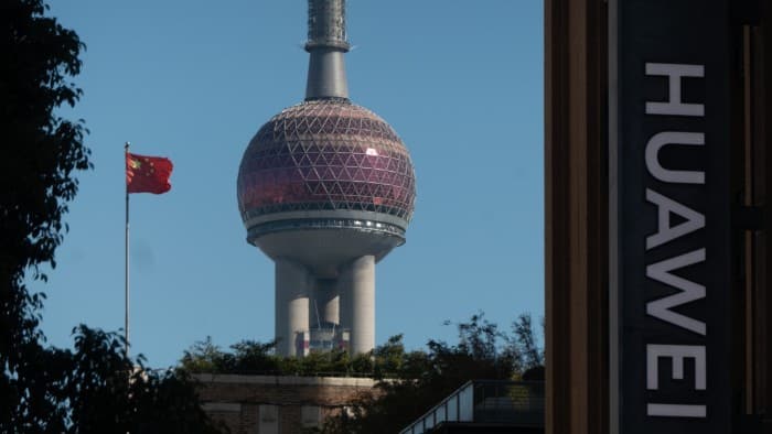 Huawei logo and the Oriental Pearl Tower near Nanjing Road Pedestrian Street in Huangpu district of Shanghai, China