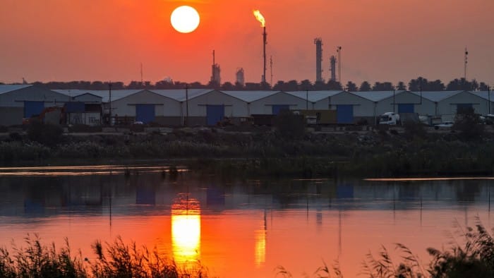 The sun sets behind burning gas flares at the Dora oil refinery in Baghdad
