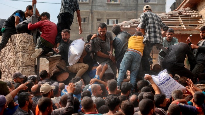People scramble to receive sacks of flour at a United Nations Relief and Works Agency (UNRWA) aid distribution centre in Deir el-Balah in the central Gaza Strip