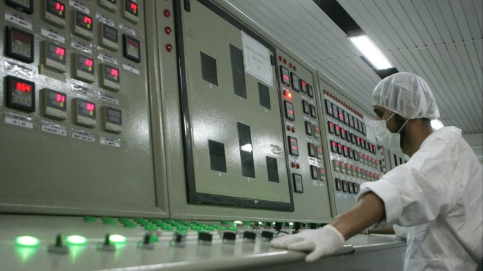An Iranian technician in overall, gloves, hairnet and facemask works in the control room of the Isfahan Uranium Conversion Facilities