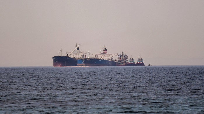 Two large oil tankers are positioned side by side in the sea