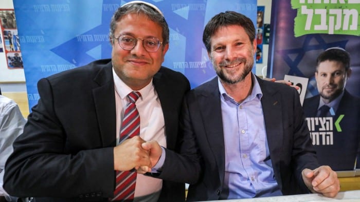 Itamar Ben-Gvir and Bezalel Smotrich are seated together, smiling and clasping hands