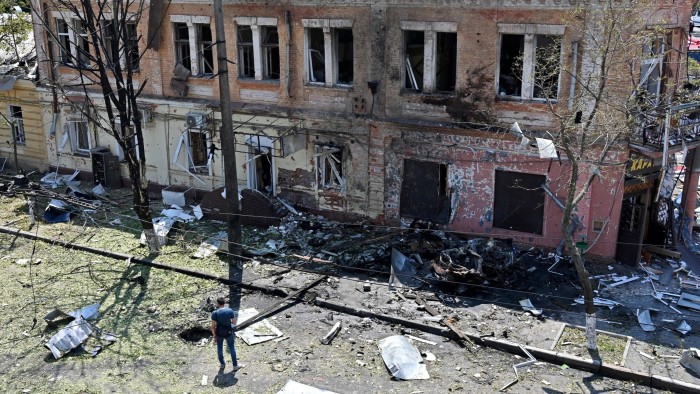 A man stands among debris next to a recruitment centre building damaged after a drone attack in Kharkiv