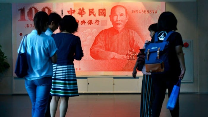 Visitors walk past a large poster of a NT0 note featuring Sun Yat-Sen