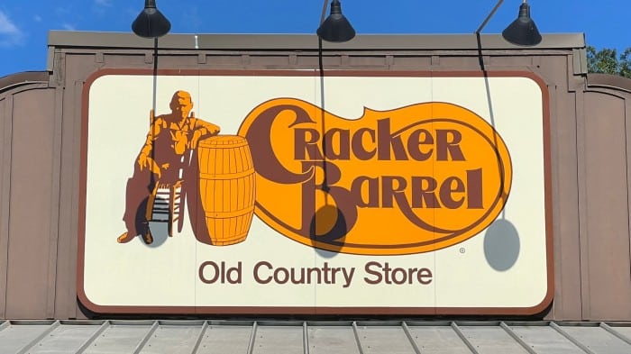 The Cracker Barrel Old Country Store logo on a large rooftop sign, featuring a man sitting beside a barrel.