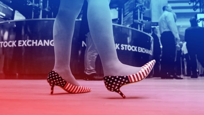 A person wearing high heels with an American flag pattern stands on the trading floor of the New York Stock Exchange
