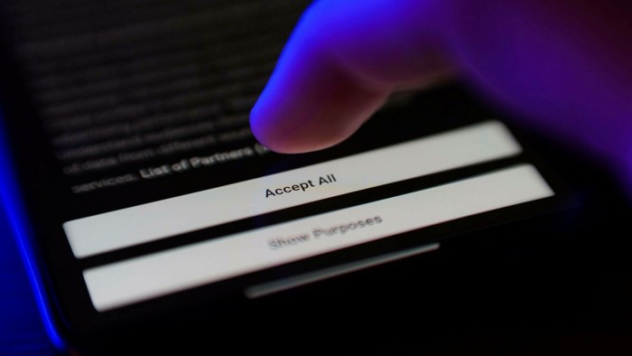 A finger hovers over a touchscreen displaying a cookie consent pop-up with the ‘Accept All’ option highlighted